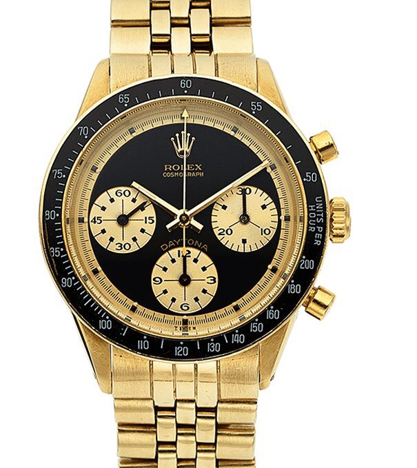 A close-up of a vintage gold Rolex Daytona chronograph watch with a black dial and gold sub-dials.