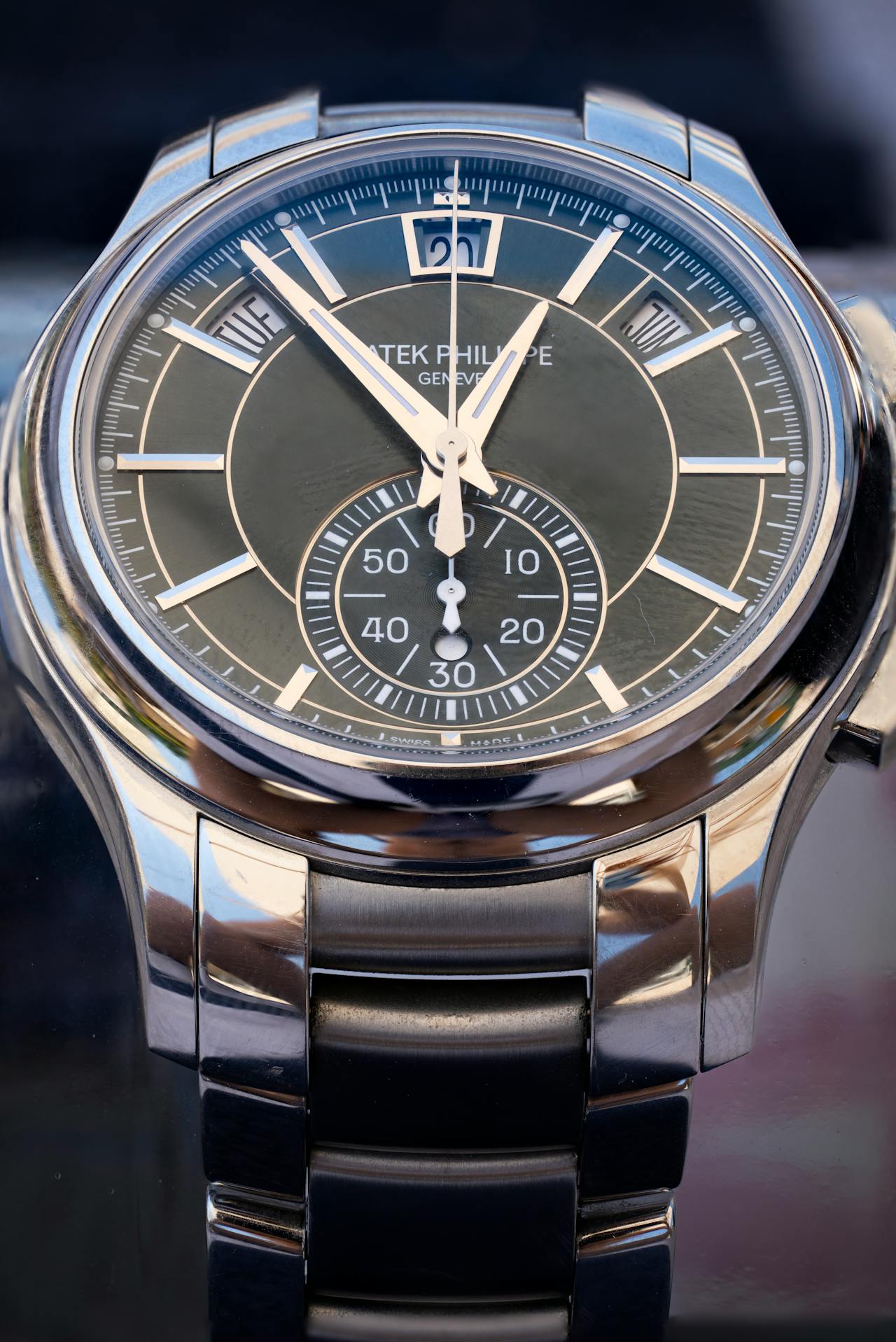 Close-up of a Patek Philippe watch with a black dial, silver numerals, and a silver metal bracelet.