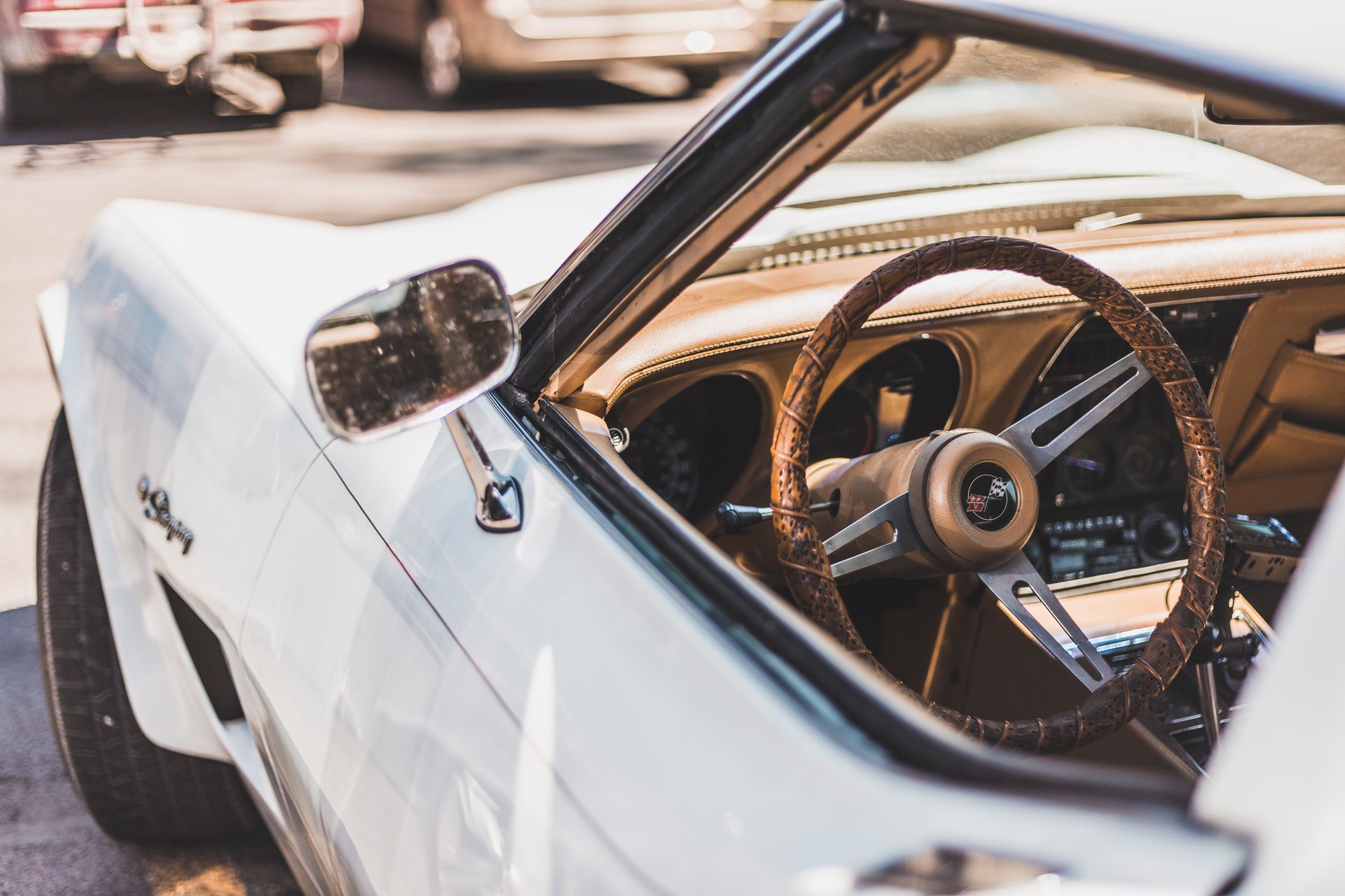 A close-up of the interior of a vintage white Corvette with a brown steering wheel.