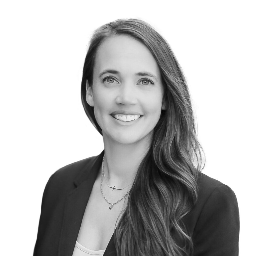 Professional headshot of a smiling woman with long hair in a blazer, looking at the camera.