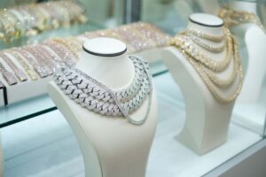 Diamond-encrusted stacked necklace on a white display bust in a jewelry store window case.